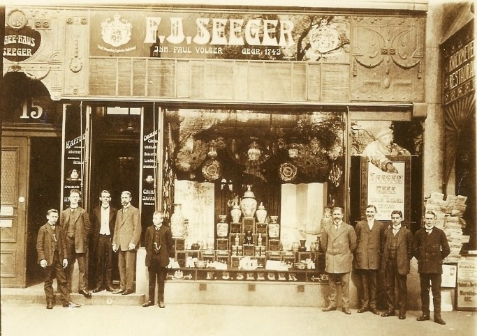 F.A. Seeger Geschäft um 1900 – Historische Außenansicht mit Schaufenster und Personal Historisches Foto des F.A. Seeger Geschäfts um 1900 mit Schaufenster und mehreren Männern vor dem Laden