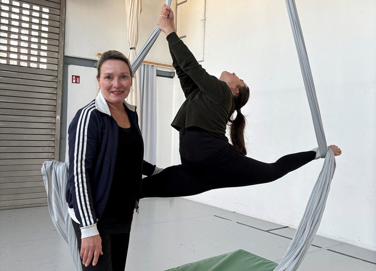 Luftakrobatik Training mit Trainerin und Schülerin am Vertikaltuch in einer Turnhalle