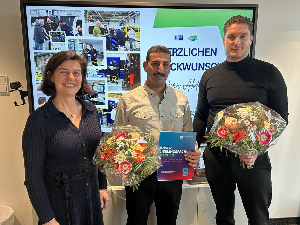Gratulation zur bestandenen IHK-Prüfung mit Blumen und Urkunde vor Präsentationsbildschirm