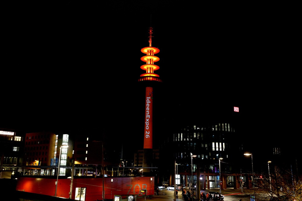 Beleuchteter Funkturm bei Nacht mit Schriftzug ideenExpo 26, Stadtansicht mit ZOB und DB-Gebäude