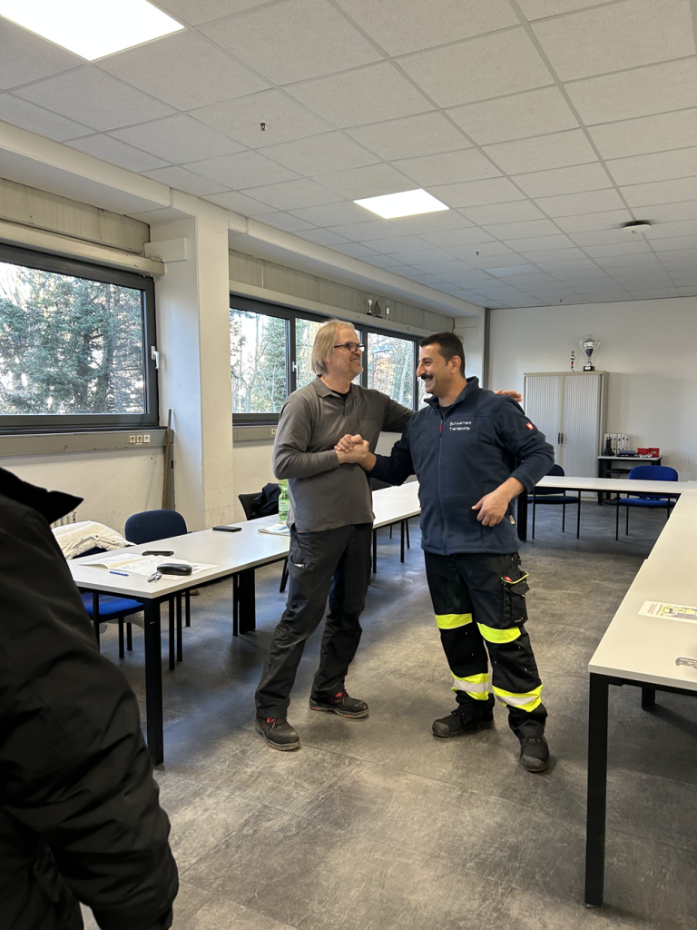 Zwei Personen in Arbeitskleidung in einem modernen Seminarraum bei einer Besprechung oder Schulung