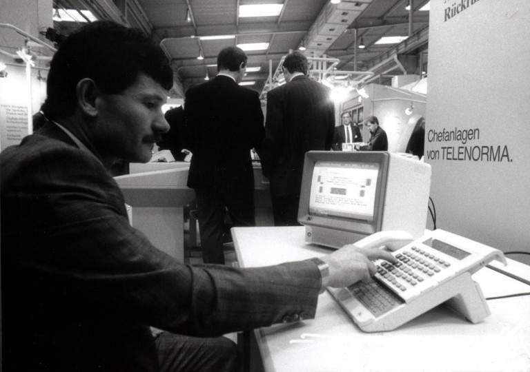 Historisches Foto vom Telenorma-Stand auf der CeBIT, Mann arbeitet an Computerterminal