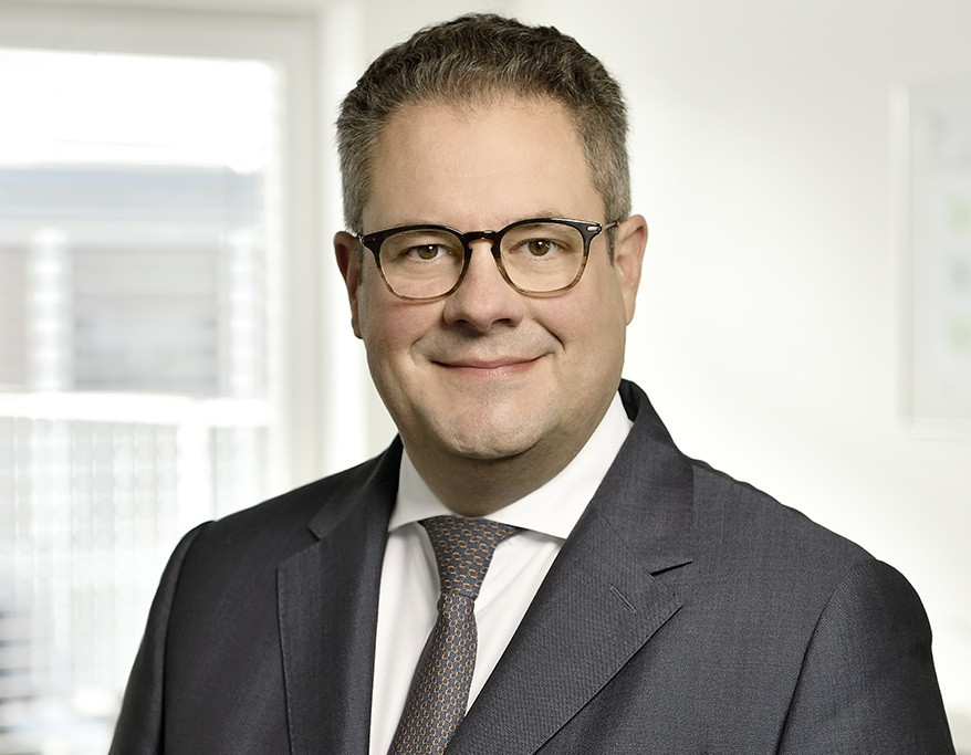 Patrick Döring von WERTGARANTIE im Business-Outfit vor hellem Hintergrund