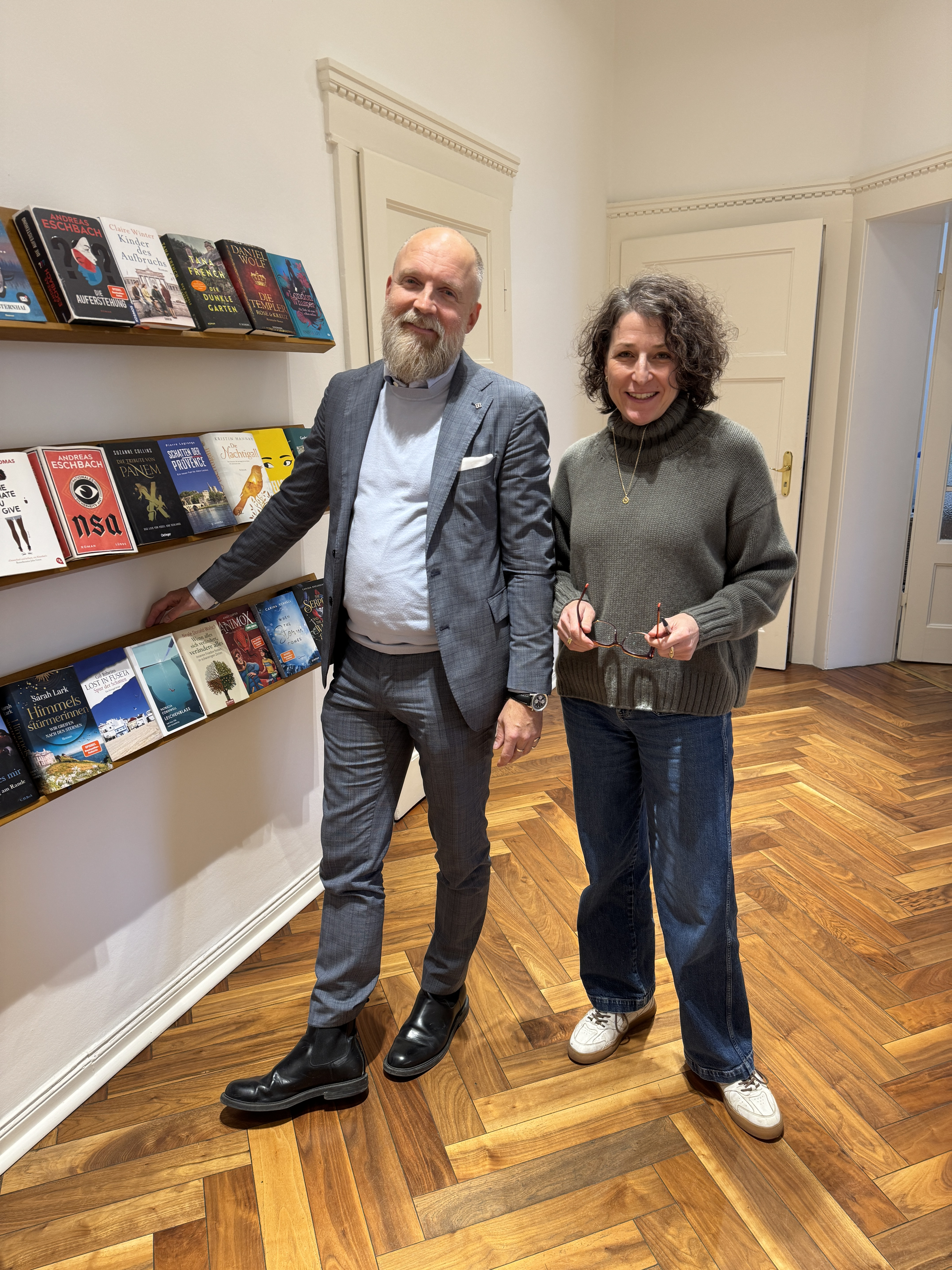 Zwei Personen stehen in einer modernen Buchhandlung vor einem Regal mit aktuellen Büchern.