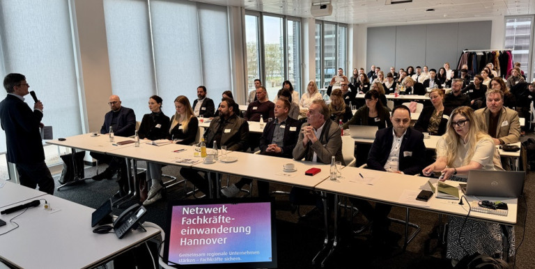 Teilnehmer einer Veranstaltung des Netzwerks Fachkräfteeinwanderung Hannover in einem modernen Konferenzraum.