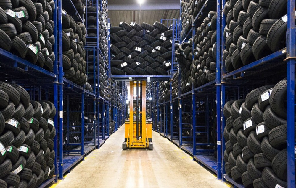 DelticomAG Lager mit gestapelten Reifen und Gabelstapler in einer modernen Lagerhalle