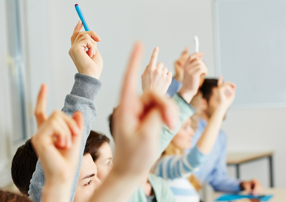 adobestock-50098231-web: Mehrere Personen heben im Klassenzimmer die Hand, um sich zu melden