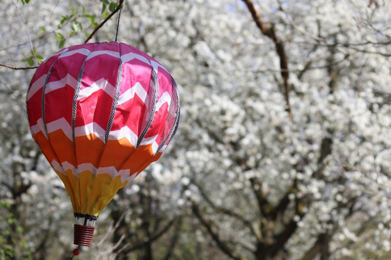 webmagazin-6 – Frühlingshafte Heißluftballon-Dekoration vor blühenden Bäumen webmagazin-6: Bunte Heißluftballon-Dekoration vor blühenden Bäumen im Frühling