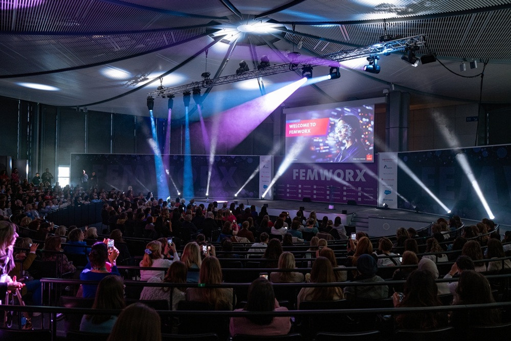 Bühne und Publikum bei der FEMWORX Konferenz, modernes Event mit Lichteffekten und großem Screen