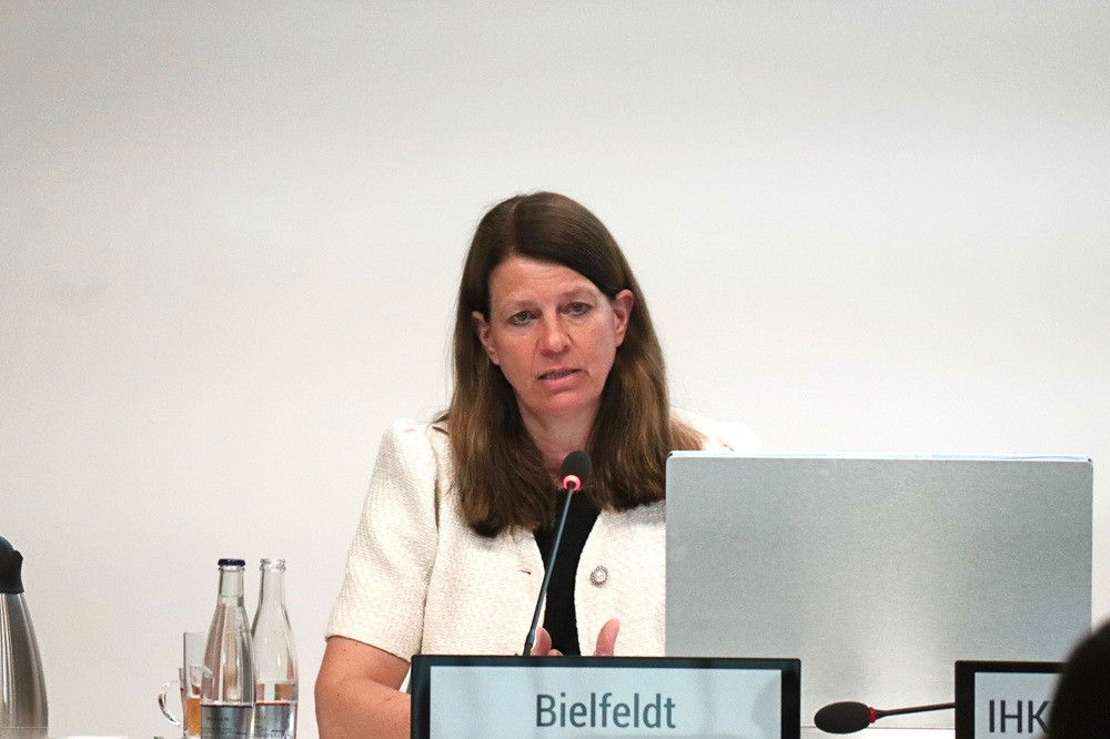 Frau bei einer Konferenz oder Podiumsdiskussion, Namensschild Bieldfeldt, spricht am Mikrofon