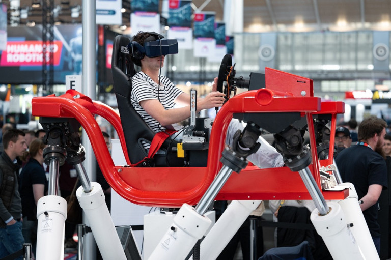 Person mit VR-Brille in einem Rennsimulator auf einer Messe – foto-webmagazin