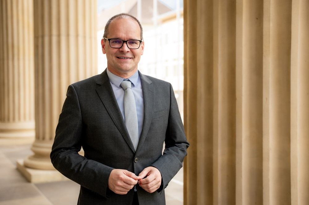 Business-Porträt von Jonah Bublitz im Anzug vor Säulengebäude