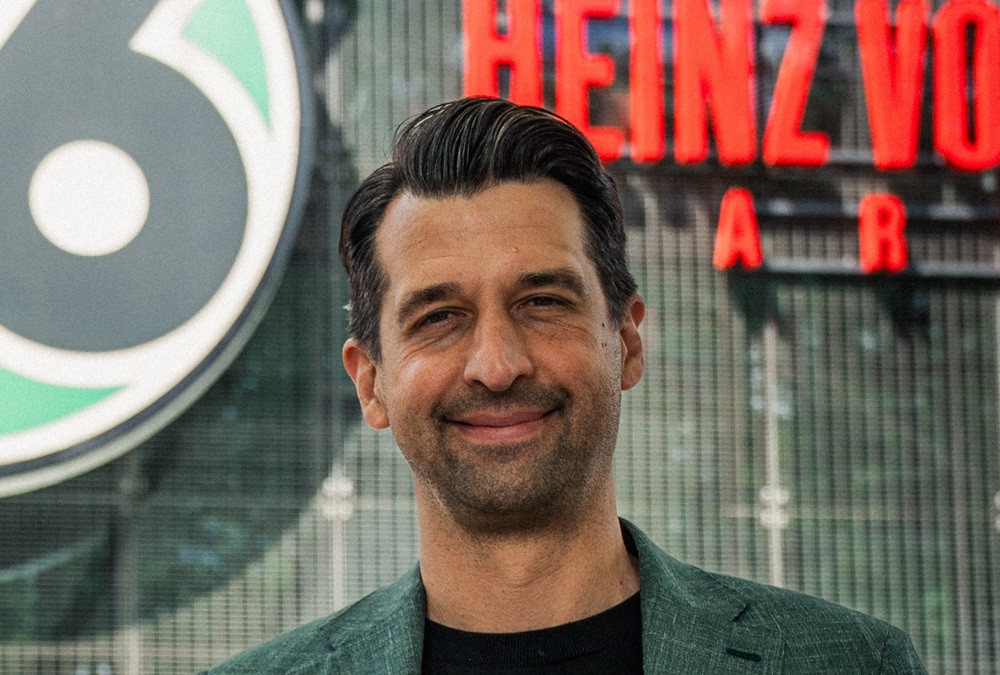 Jonas Boldt vor dem Logo von Hannover 96 im Stadion
