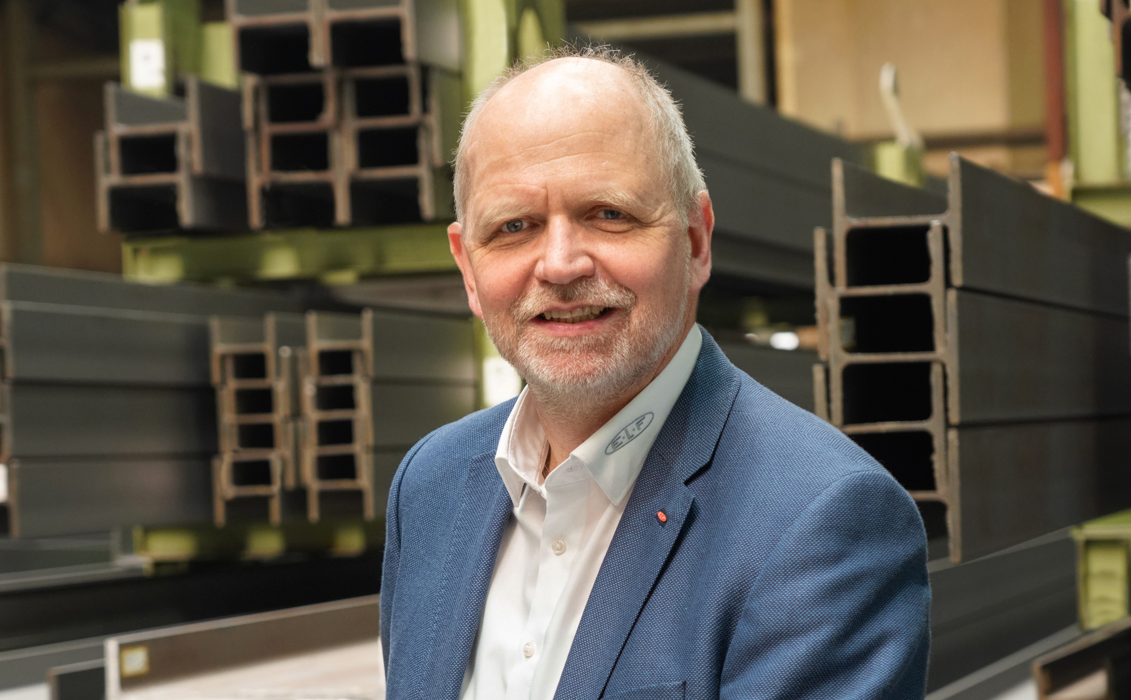 Porträt eines Mannes im Anzug vor Stahlträgern in einer Industriehalle