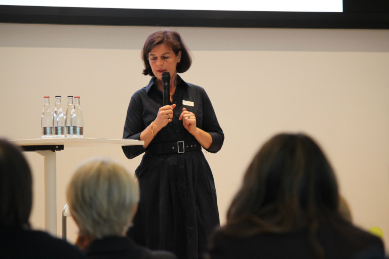 Vortragende Frau auf Konferenz oder Event mit Publikum Frau hält Vortrag auf einer Konferenz oder Veranstaltung, Publikum im Vordergrund