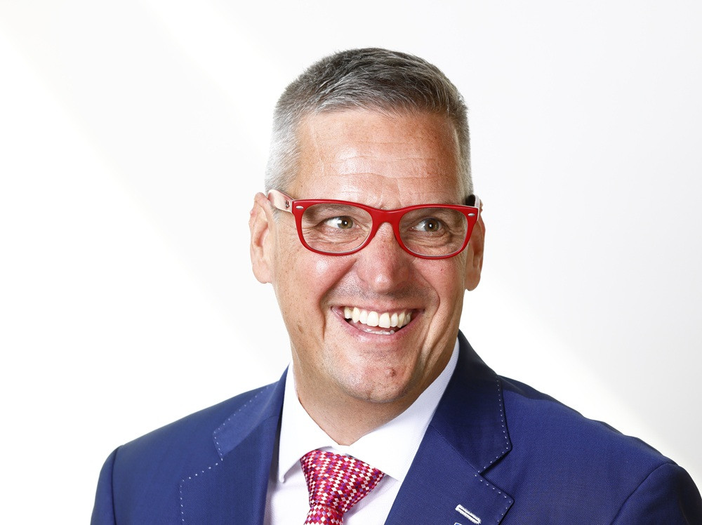 Porträt von Jörg Hickmann, RWS, mit roter Brille und blauem Anzug