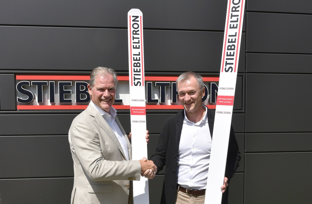 Zwei Me4nner beim Handschlag vor einem STIEBEL ELTRON Schild mit Skisprung-Ski, skisprung-01-web