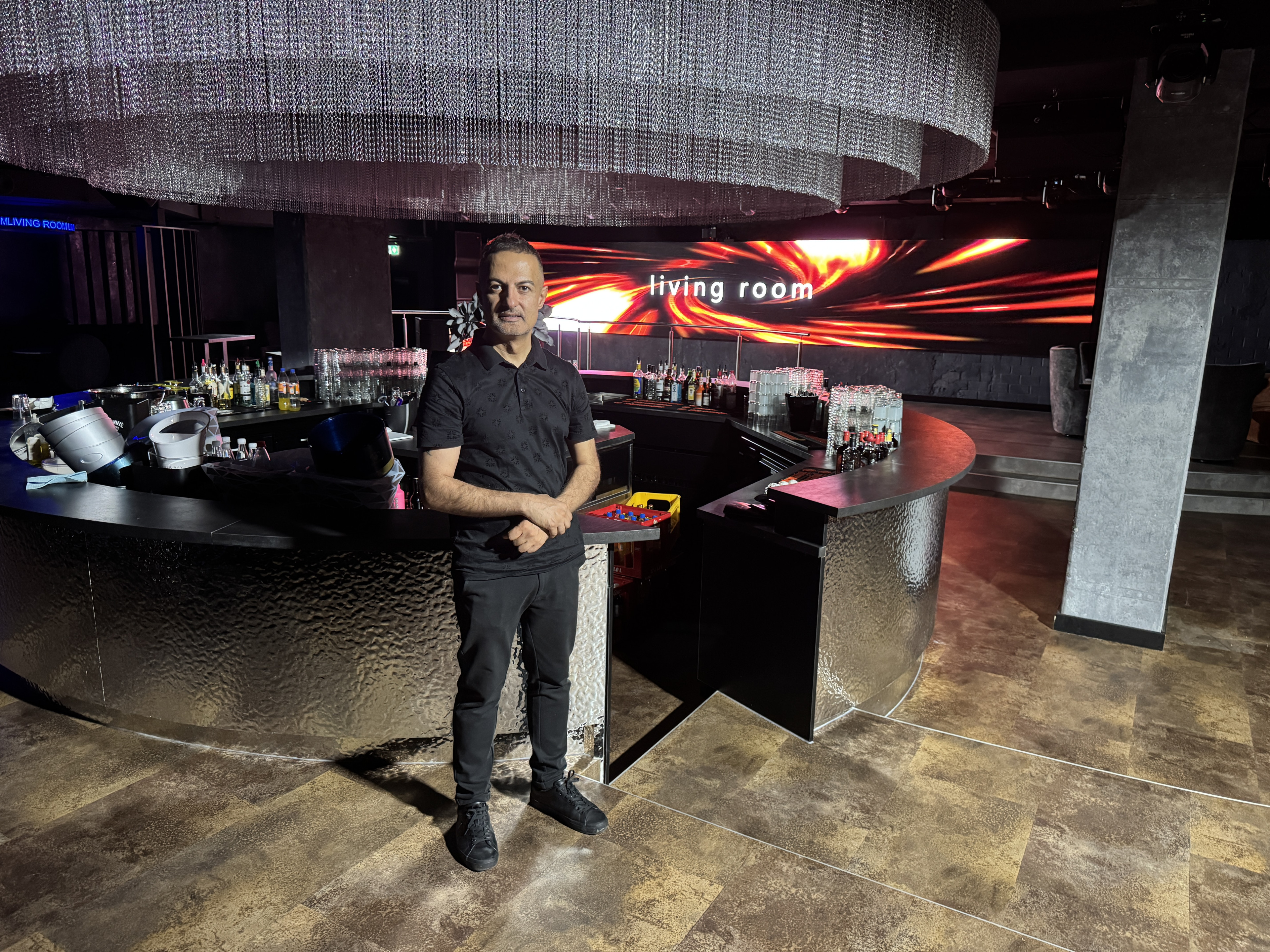 Mann steht an einer modernen Bar im Club Living Room mit stilvoller Beleuchtung