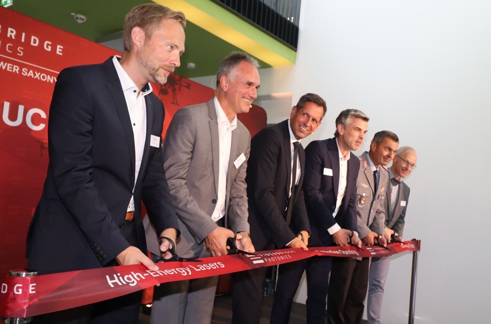 Eröffnung der UNT Fiberbridge mit mehreren Personen beim Durchschneiden eines roten Bandes, High-Energy-Lasers und Photonics Schriftzug sichtbar