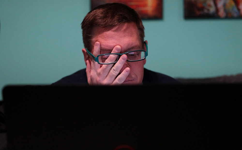 acwells man mit Brille sitzt nachdenklich vor Laptop
