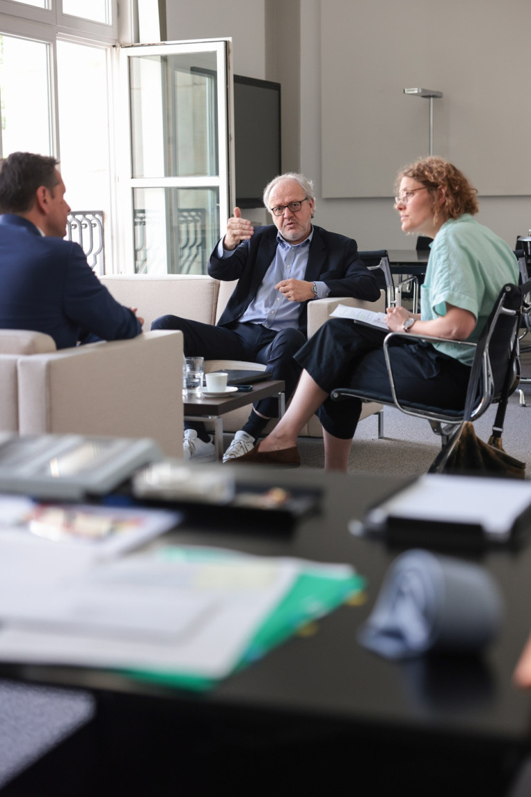 Interview-Runde mit drei Personen in einem modernen Büro, Gesprächssituation am Tisch