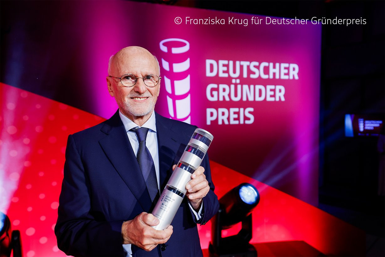 Dirk Rossmann erhält den Deutschen Gründerpreis und hält die Auszeichnung in der Hand