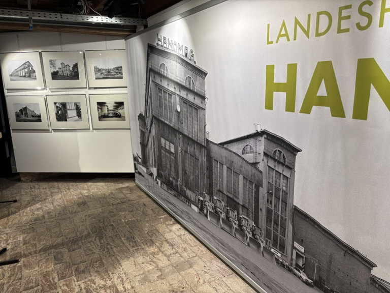 Ausstellungsansicht mit großem Wandbild der Hanomag-Fabrik und historischen Fotografien