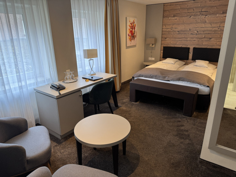 Modern eingerichtetes Hotelzimmer mit Doppelbett, Schreibtisch und Sitzbereich