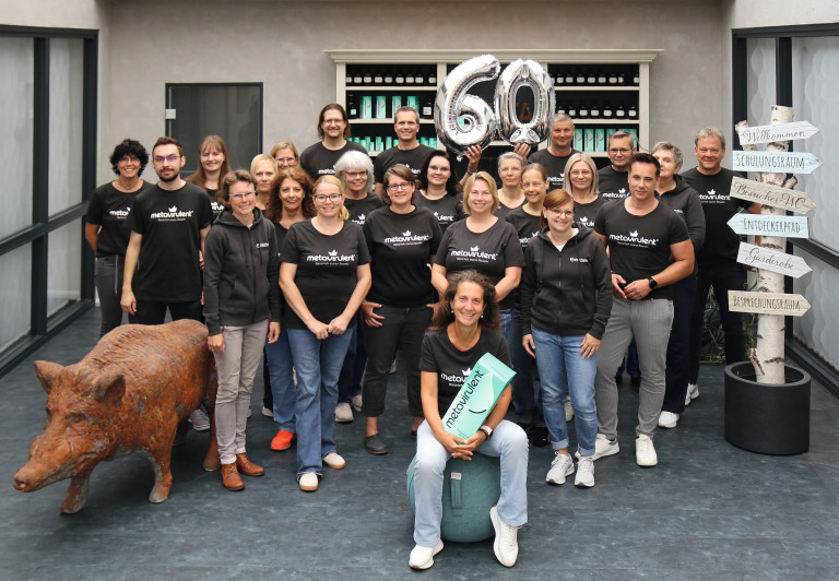 Teamfoto zum 60-jhrigen Jubilum, Mitarbeitende mit metavulent-Shirts und 60er-Ballon Gruppenfoto eines Teams mit metavulent-Shirts, Jubilum 60 Jahre, Menschen halten Ballons mit der Zahl 60