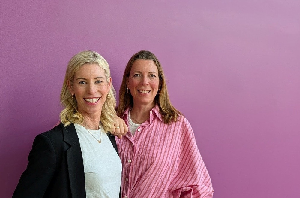 Katja und Constanze vor einer lila Wand, freundliches Portraitfoto
