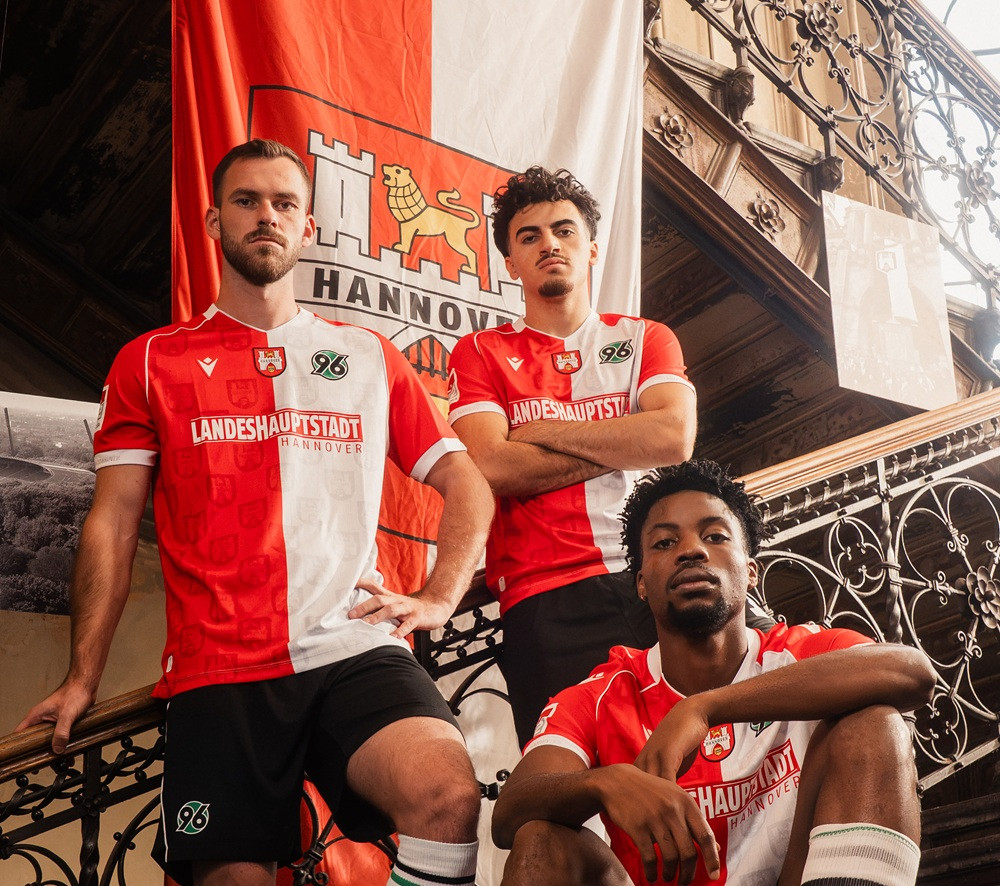 Sondertrikot von Hannover 96 mit Landes­hauptstadt Hannover Schriftzug, drei Spieler posieren vor einer Hannover-Fahne