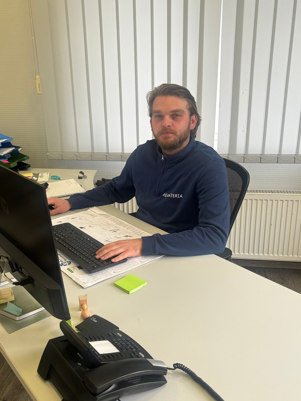 Mitarbeiter im Büro arbeitet am Computer und trägt ein CREATERIA Sweatshirt