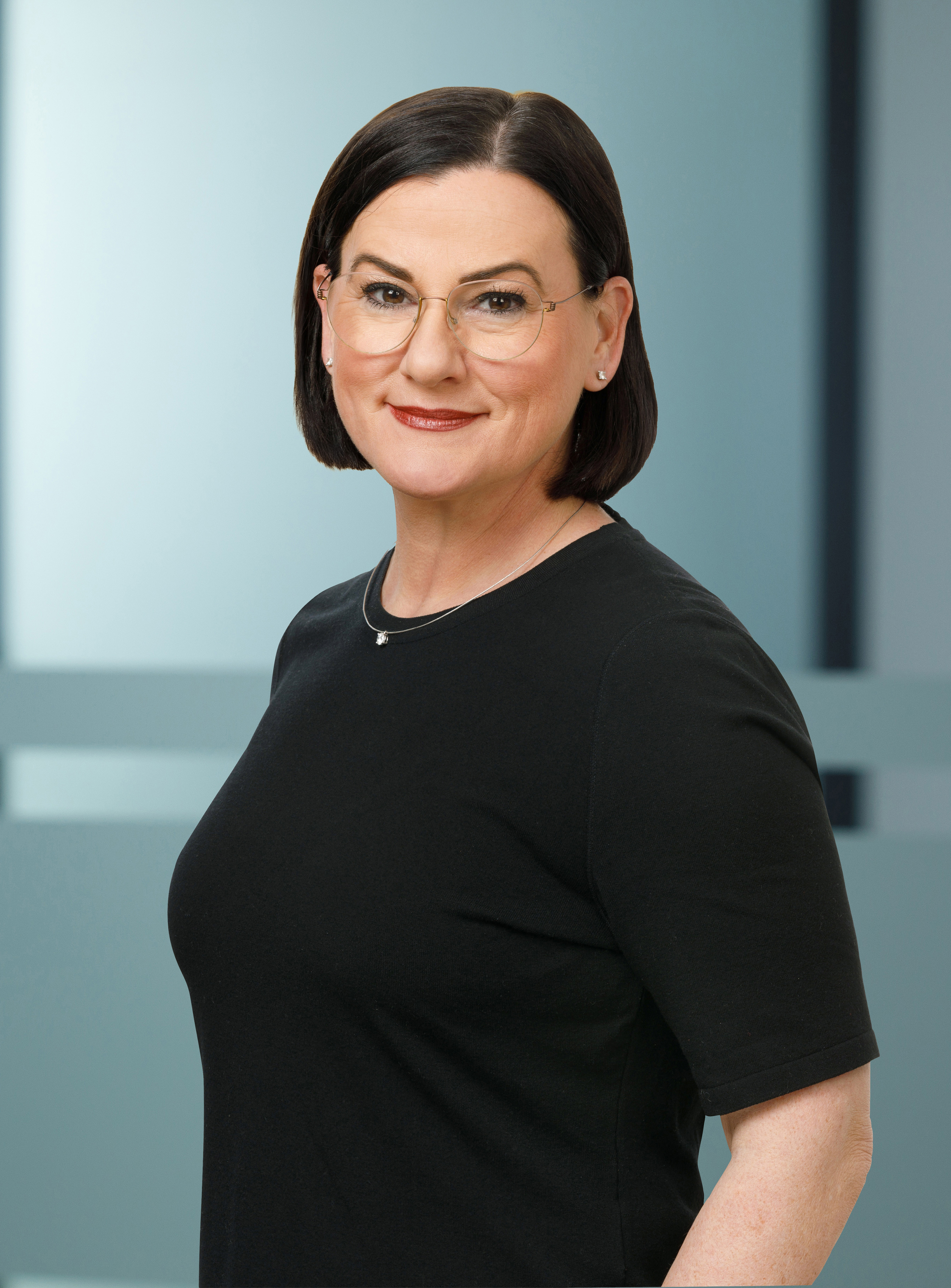 Business-Porträt einer Frau mit schwarzem Oberteil vor modernem Hintergrund, cg-7697-0-4