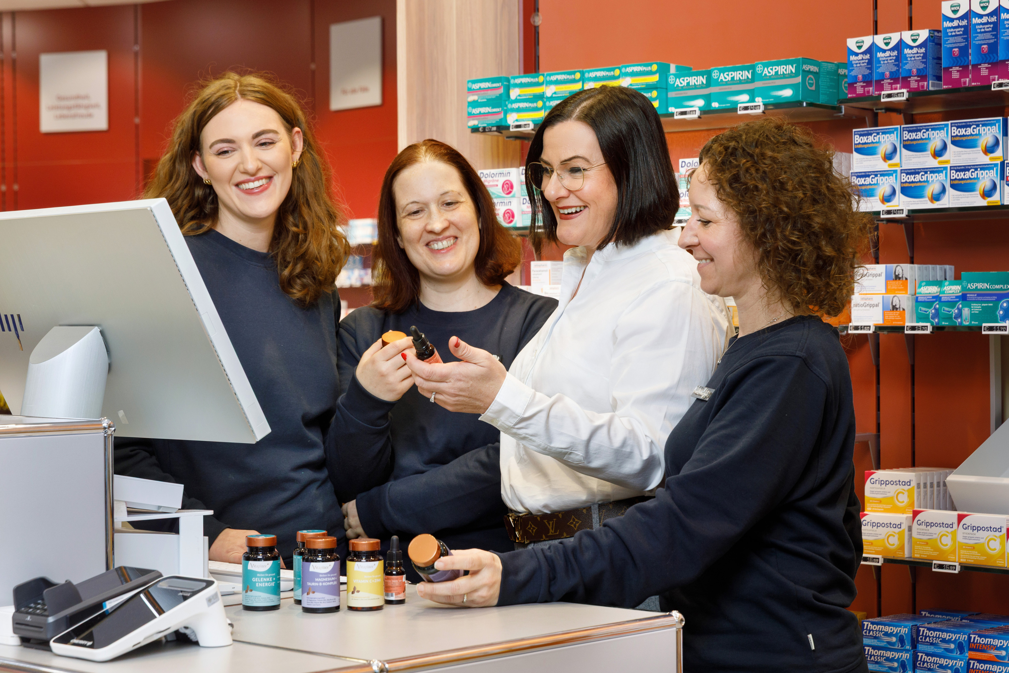 Beratung zu Nahrungsergänzungsmitteln in einer Apotheke mit verschiedenen Produkten am Tresen