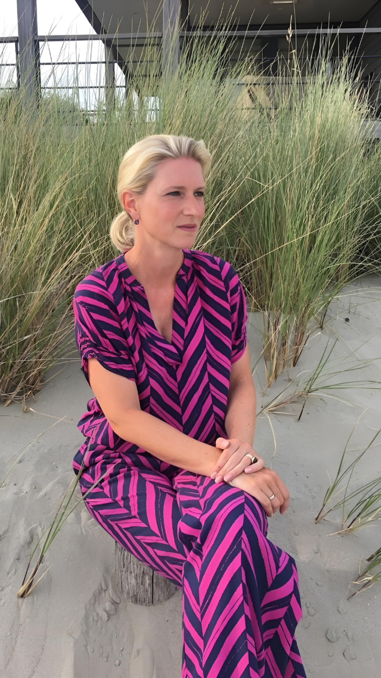 Caroline Prenzler sitzt entspannt am Strand und blickt aufs Meer