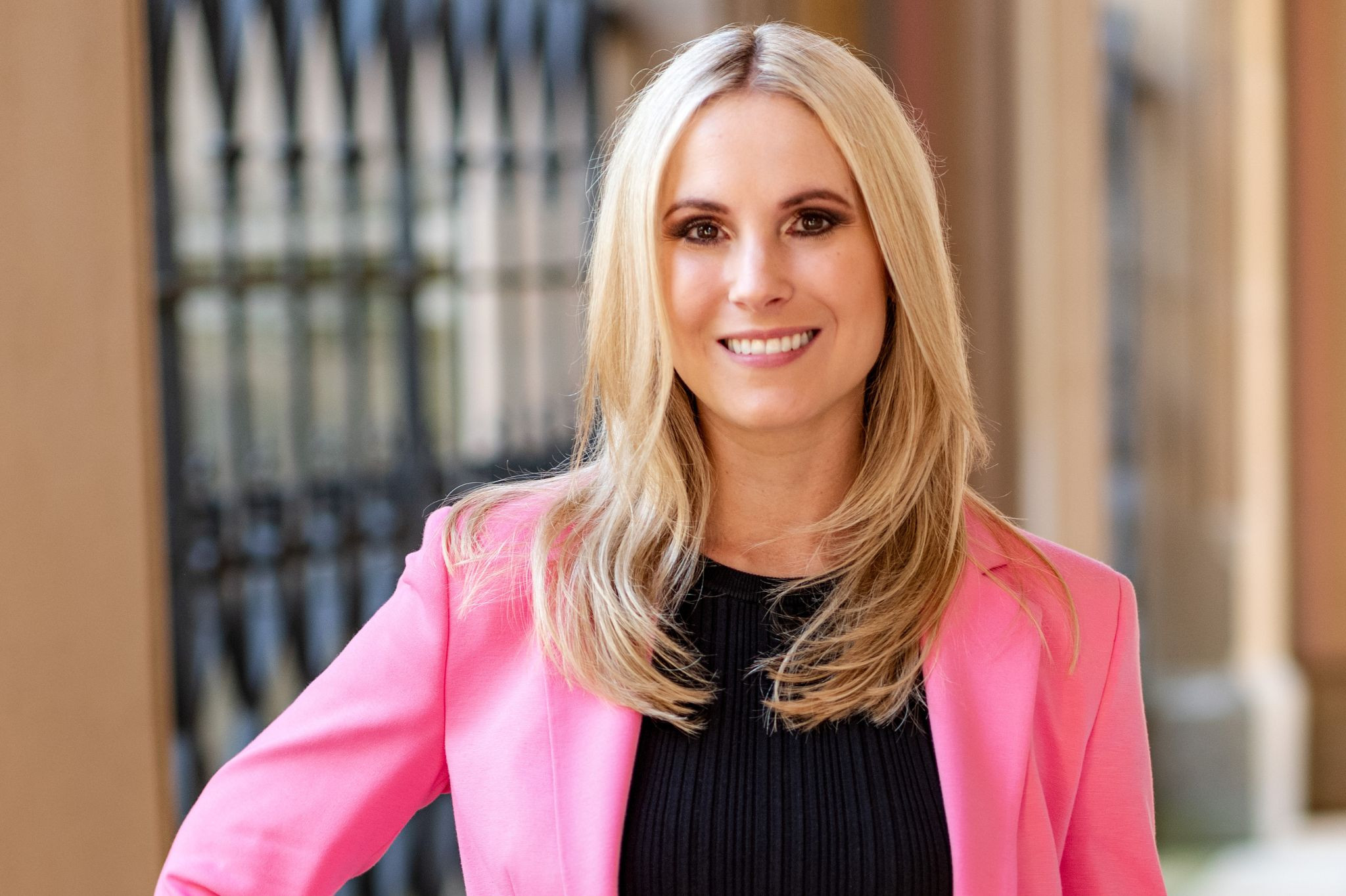 Porträt einer lächelnden Frau in einem rosa Blazer