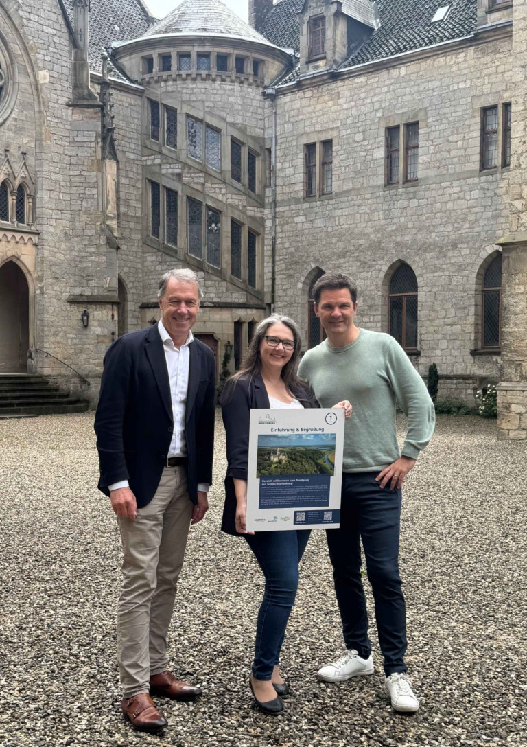 Besucher vor dem Schloss Marienburg mit Informationsschild