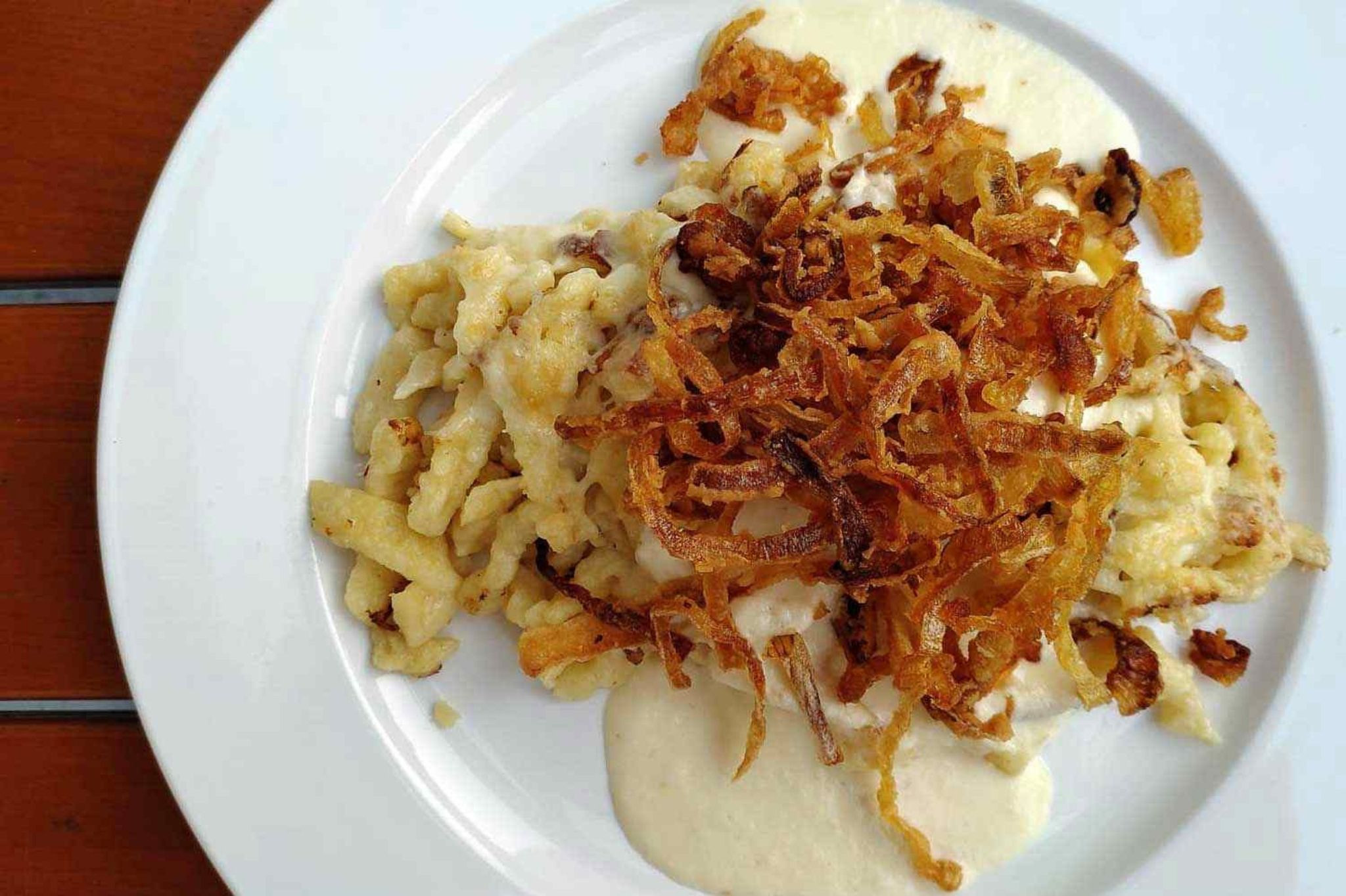 Spätzle mit Zwiebeln und Sauce im Spätzle-Haus Spätzle mit knusprigen Zwiebeln und cremiger Sauce auf einem Teller