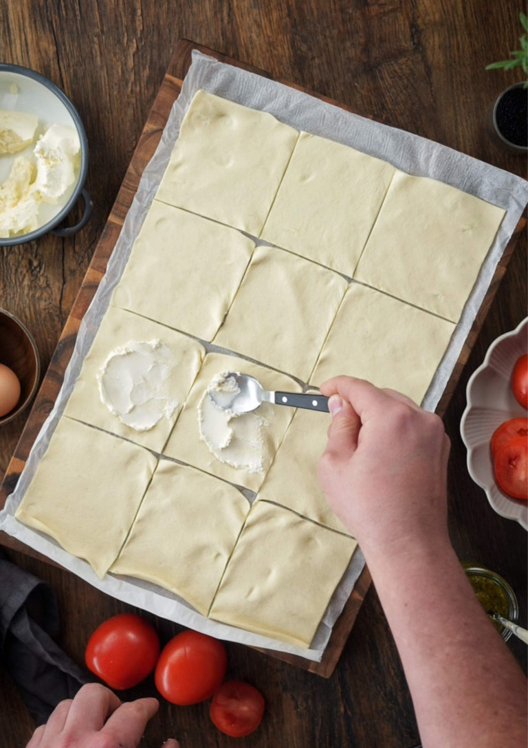 Zubereitung von Blätterteig mit Frischkäse auf einem Holztisch