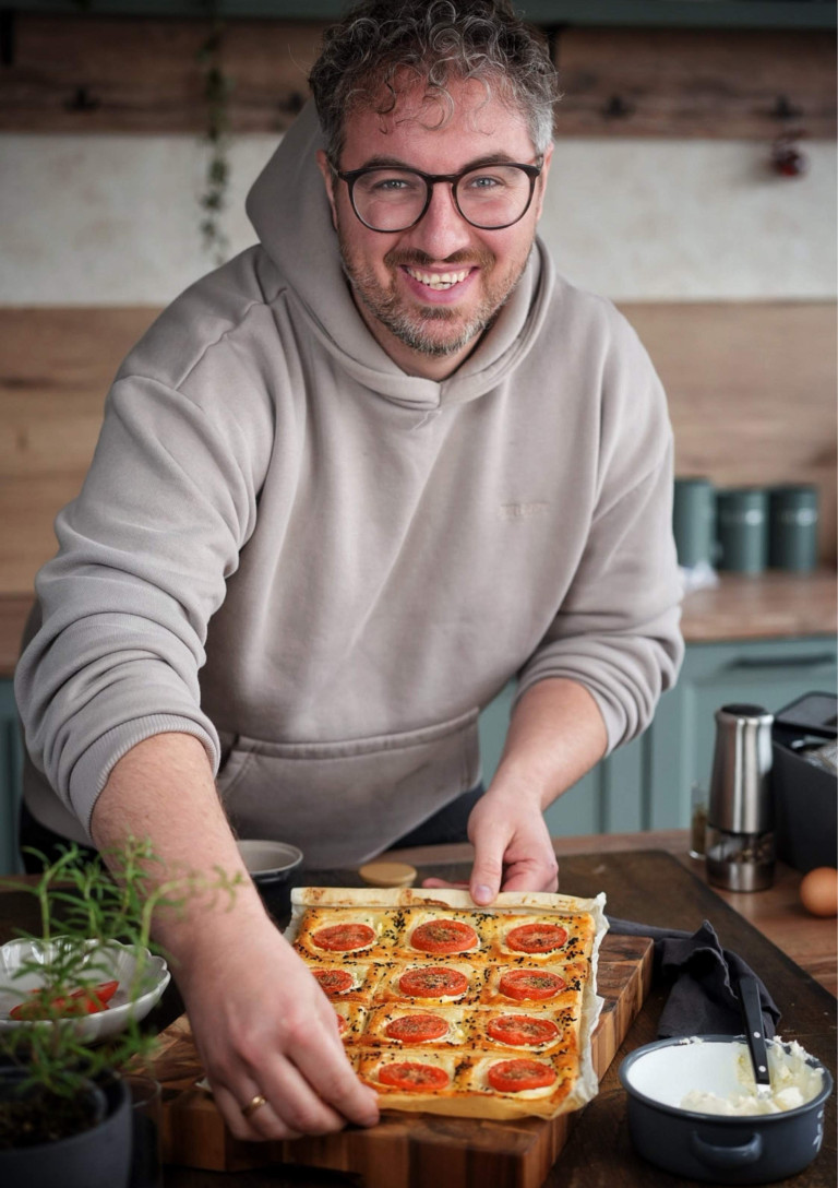 Person in der Küche bei der Zubereitung von Blätterteig mit Tomaten