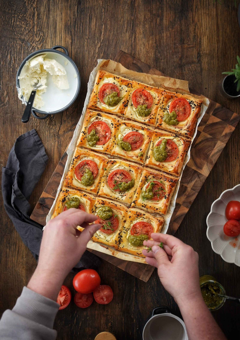 Blätterteig mit Tomaten und Pesto auf einem Holzbrett