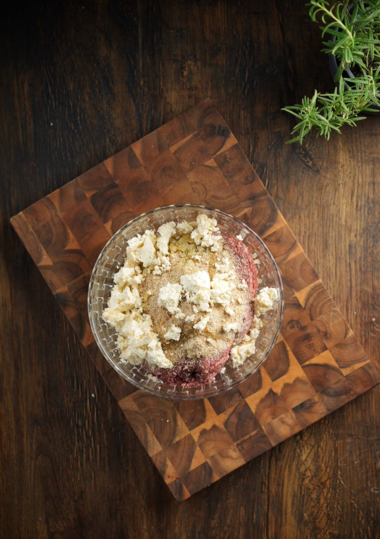 Hackfleisch mit Gewürzen und Käse auf einem Holzbrett