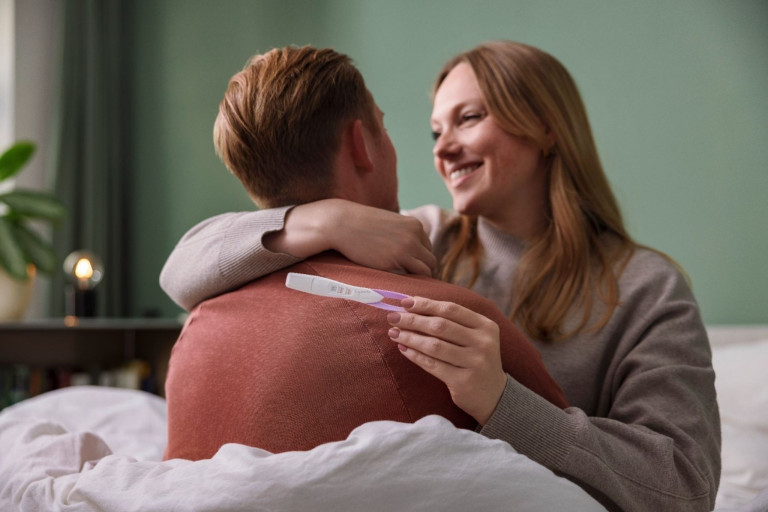 Lächelndes Paar mit Schwangerschaftstest in der Hand