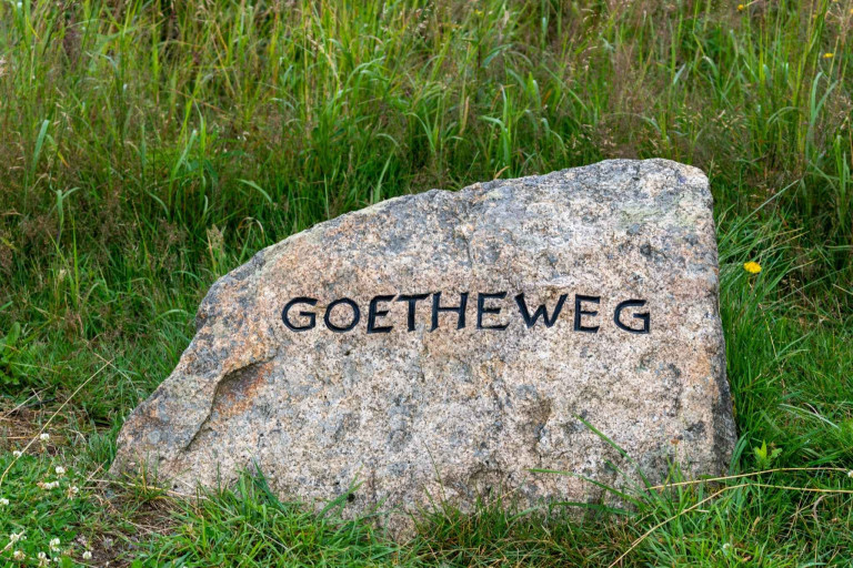 Stein mit der Aufschrift Goethewg Stein mit der Aufschrift Goethewg in einer grünen Landschaft