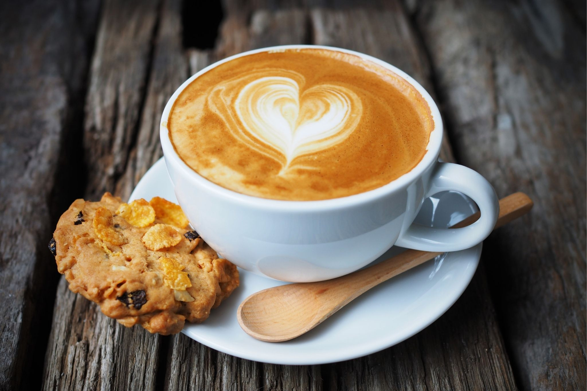 Genusstipp: Cappuccino mit Latte Art und Keks Cappuccino mit Latte Art und Keks auf Holztisch