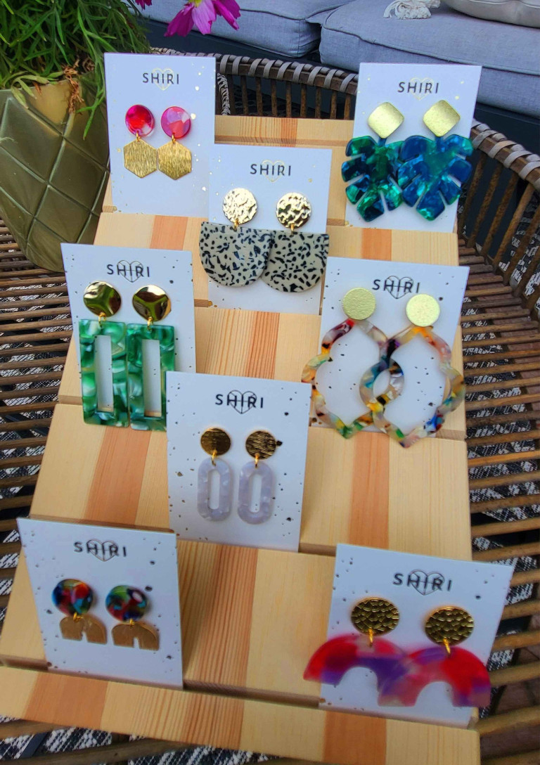 Verschiedene bunte Ohrringe von SHIRI auf einem Display aus Holz ausgestellt