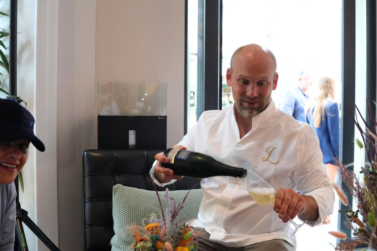 Gast gießt Sekt in einem modernen Living Bistro ein