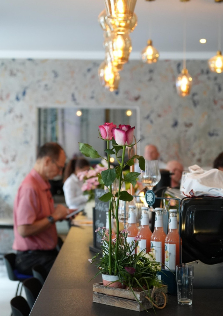 Innenansicht von The Living Bistro mit Rosen und Getränken auf dem Tresen