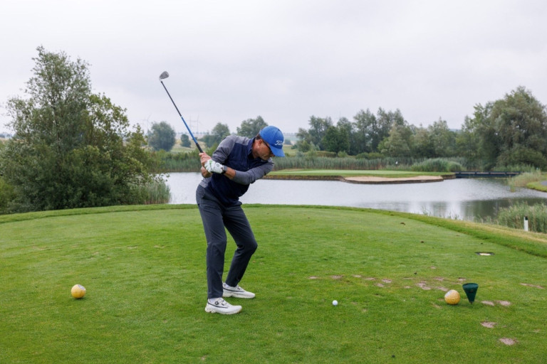 Golfspieler beim Abschlag auf einem Golfplatz mit Wasserhindernis