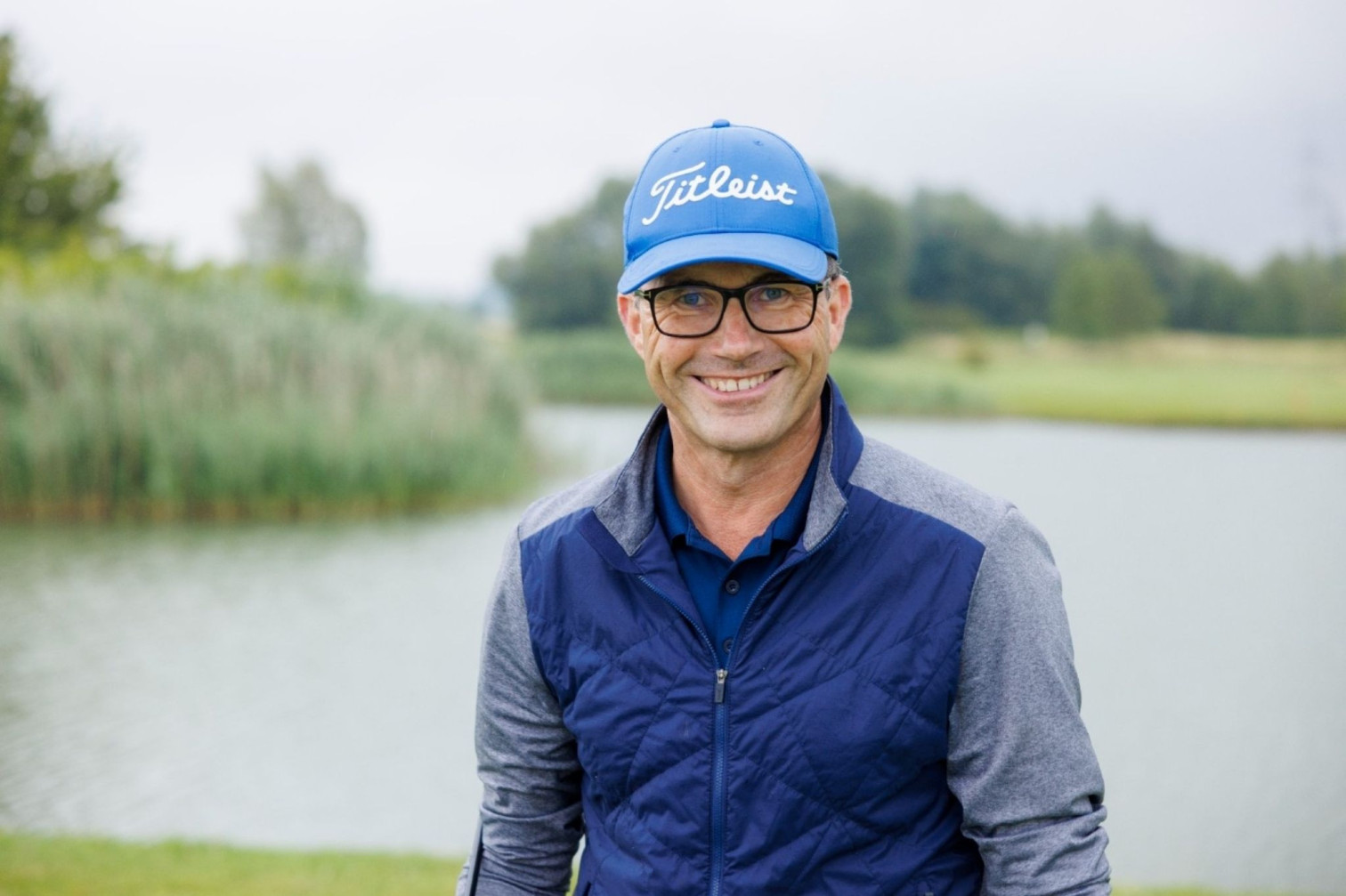 Mann mit blauer Titleist-Kappe und blauer Jacke auf einem Golfplatz – L46cher fragen Aufmacher
